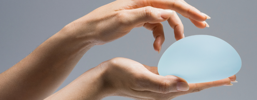 women's hand holding a Motiva breast implant