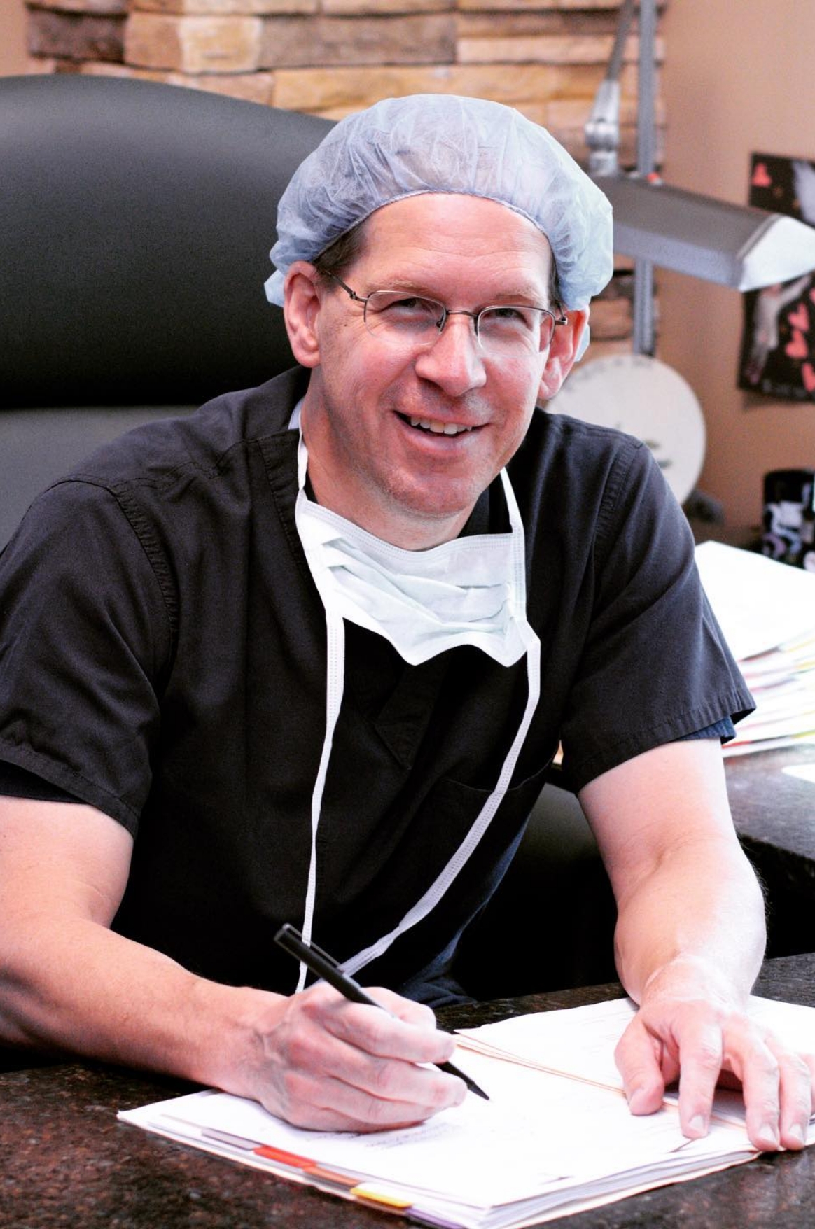 Dr. Steinwald sitting at desk smiling signing off some documents