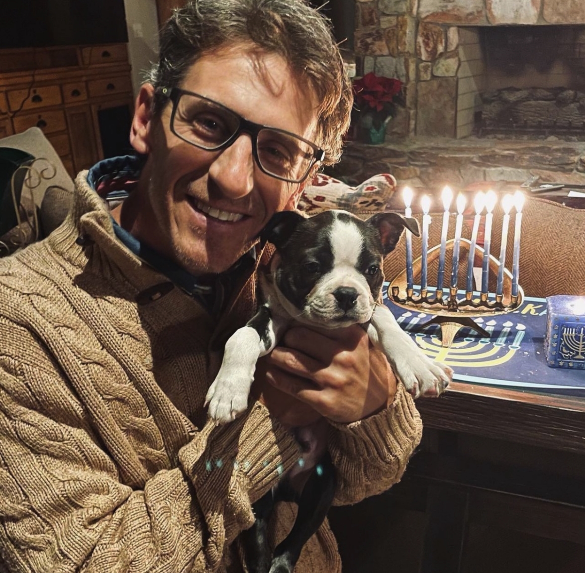 Dr. Vath celebrating Hanukkah holding a small pug puppy